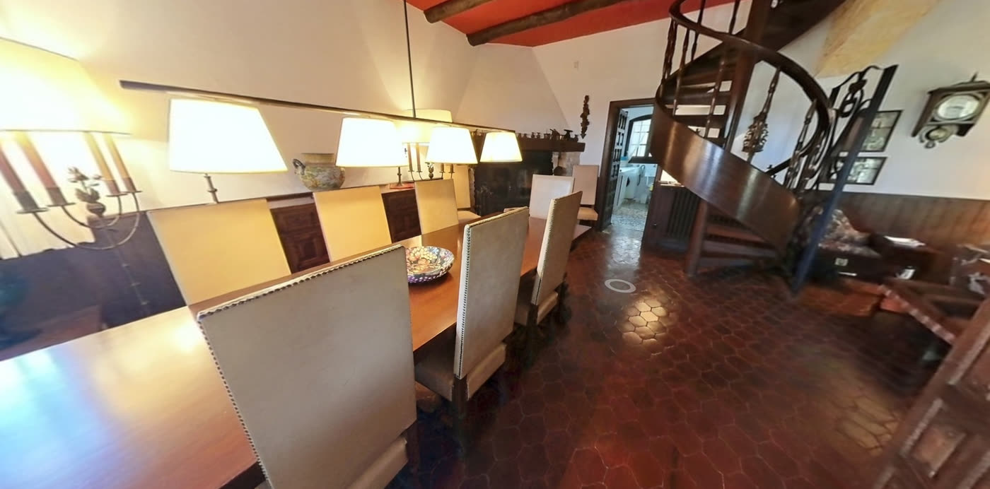 Comedor con escalera de caracol de forja y suelo de barro