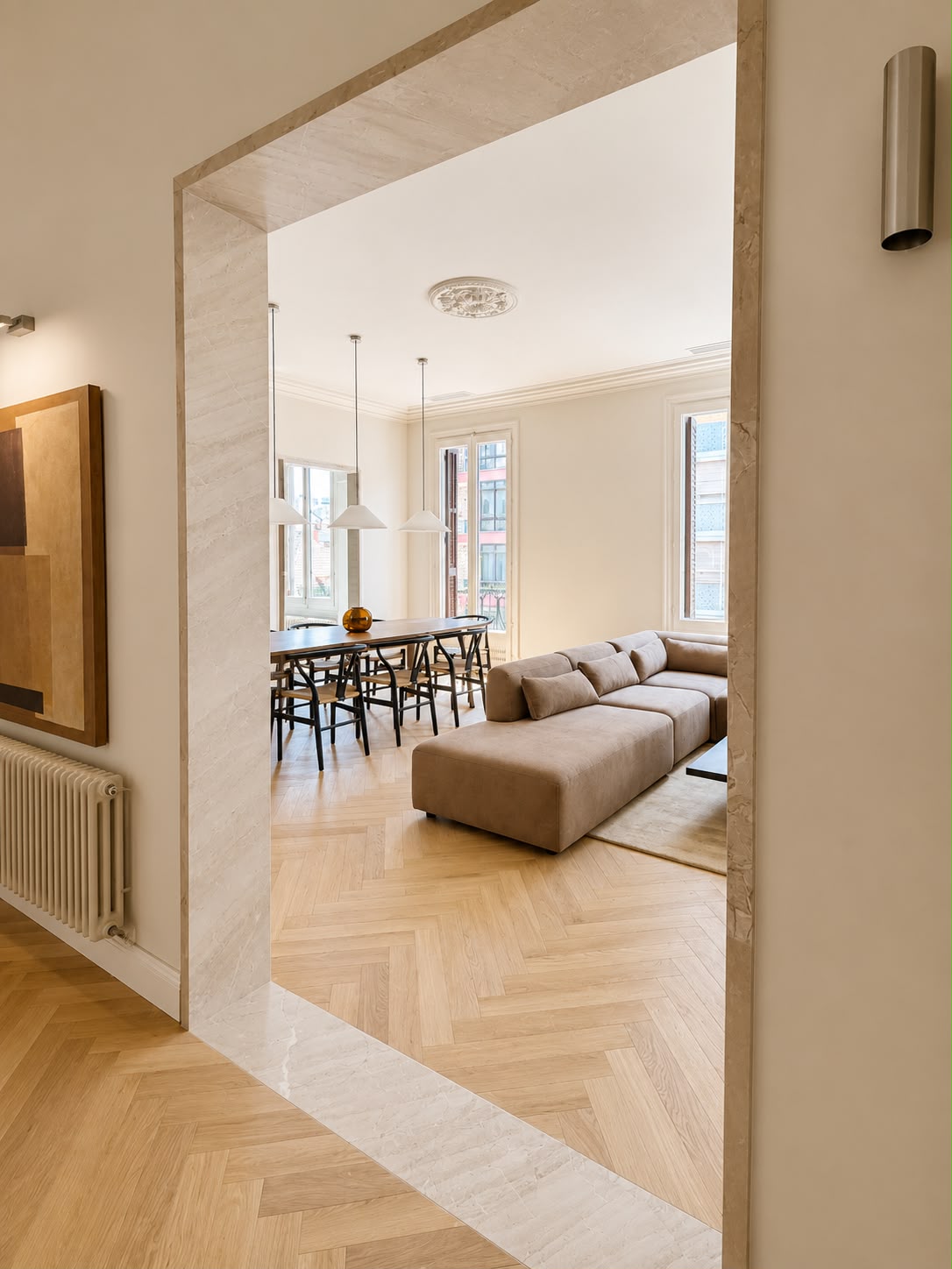 Salón y comedor en una sola pieza, con el sofá modular junto a los balcones y el parquet de roble en espiga
